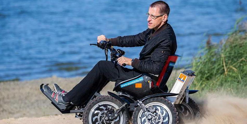 Ein Mann fährt mit dem motorisierten Rollstuhl "Zoom" über den Strand.